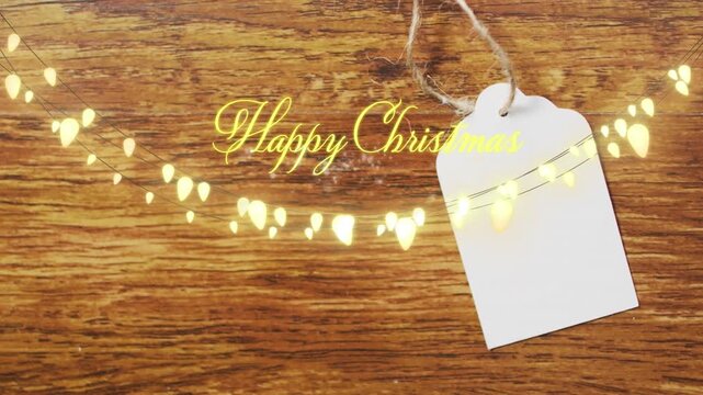 Animation of happy christmas text with fairy lights over gift tag
