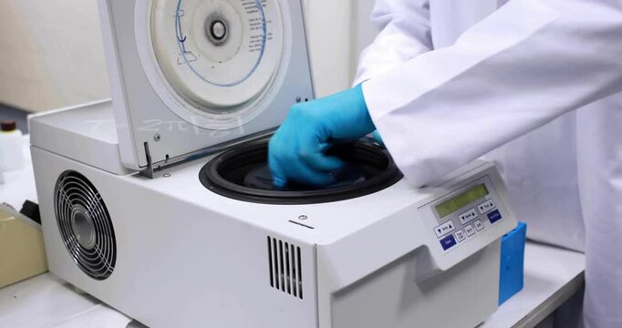 Operating laboratory centrifuge, scientist wearing blue gloves with animation of formulas