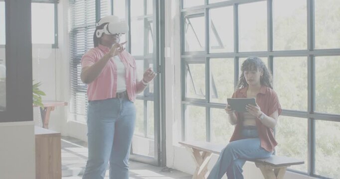 Standing user putting on VR headset, gesturing while seated user testing tablet, tech UI reacting