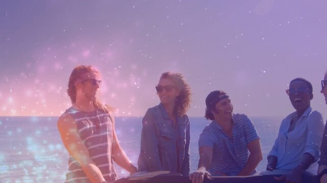 Five friends leaning rail by sea, camera panning while sparkle boosting smiles for travel ad