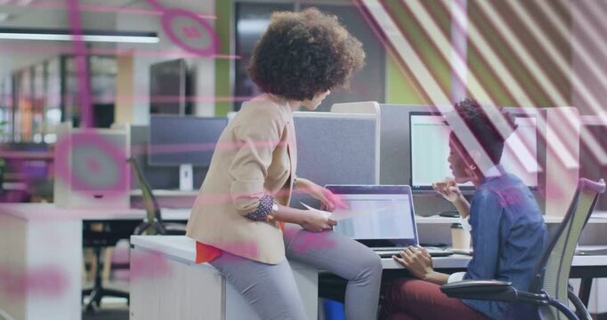 Vertical video: Standing woman leaning in showing printouts, two peers reviewing laptop for update