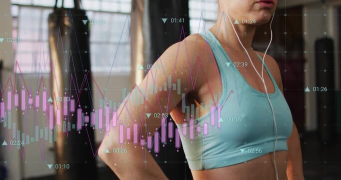 Camera pulling back showing woman pausing post-set at gym in sportsbra earphones bags data overlay