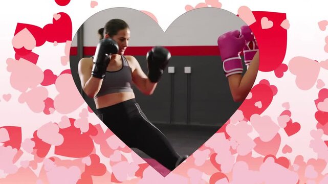 Vertical video: Kicking, two women in sports bras, pink or black gloves trading jabs, training at gy