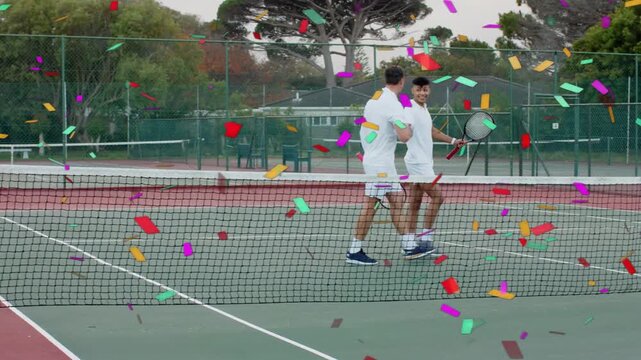 Vertical video: Four male tennis players moving to net after confetti falls, celebrating match end