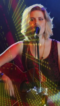 Vertical video: Singer after focus strumming while projections animating across face,guitar music