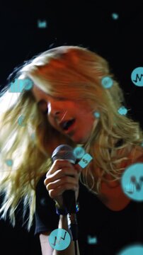 Vertical video: Lead singer gripping wired mic in club, causing teal finance icons obscuring faces