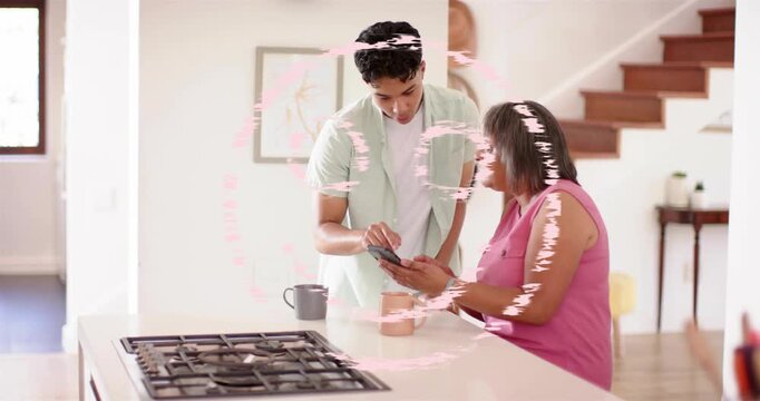 Adult son leaning, tapping phone, activating pink circular graphic, assisting senior with tech