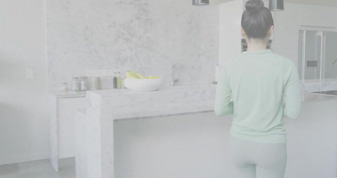 Woman descending staircase, checking phone, moving to marble island, pouring bottle for health