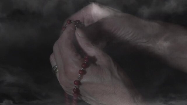 Hands starting as fingers sliding red rosary beads, grasping cruciform, swinging, suggesting prayer