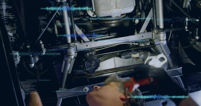 Auto mechanic turning work lamp and probing sway arm, checking boot at steering rack to inspect