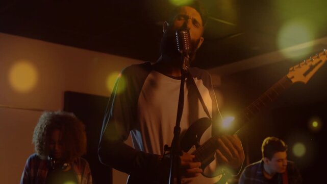 Camera pulling back revealing lead singer entering frame at vintage mic, playing guitar, rehearsing
