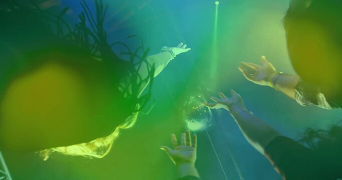 Concert attendees reaching for clear sphere on thin cord as sphere glowing and beams creating haze