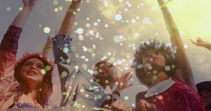 Three adults raising arms, cheering as festival music starting, confetti bokeh drifting over faces