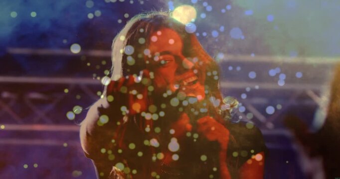 Lead singer stepping into spotlight singing to mic engaging music crowd bokeh floating across frame