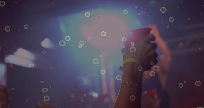 Fan raising red cup at concert celebrating while performer singing, bubbles drifting around cup