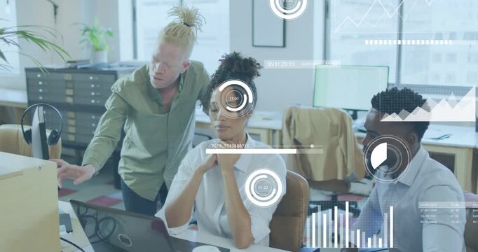 Standing man pointing at monitor initiating HUD charts while seated team discussing business data