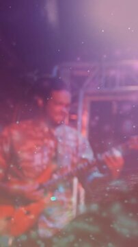 Vertical video: Sparkle clearing, revealing musician playing guitar for concert crowd filming phone