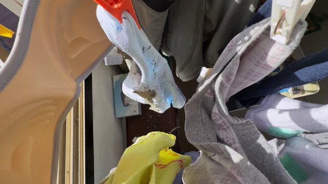 Close-up view of socks and small garments clipped to an indoor drying rack beside a sunlit window, highlighting domestic laundry care, fabric texture, and everyday household routine in natural dayligh