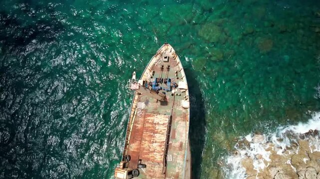 Aerial top-down view of the edro iii shipwreck rusting near the rocky shore of pegeia, cyprus