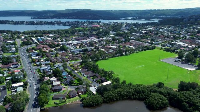 Drone aerial landscape of East Gosford rural town housing and sports field oval with Brisbane Water and bushland forest mountains in the background Central Coast Australia infrastructure and tourism