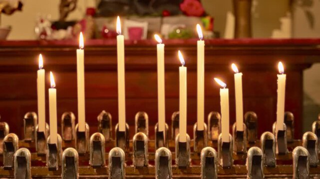 Burning votive candles in christian church by alter with flame and warm light. Faith and religion inside cathedral in European country. Altar candles lights for honor and prayer. Worship ceremony