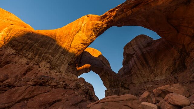 Double Arch sunrise in Arches National Park, golden light hitting rock, Utah, USA. time lapse zoom in