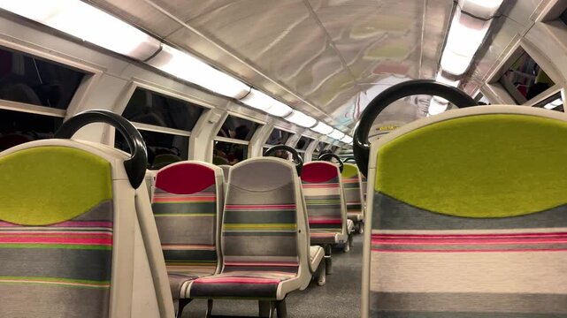 Interior of a passenger train in France heading toward Paris, featuring modern seating with colorful patterns and overhead lighting. The scene highlights comfort and public transportation in Europe