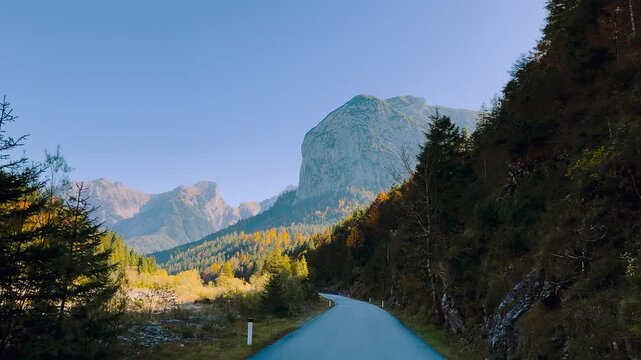 Winding autumn road through Karwendel forest along Rissach river, Engtal valley, Tyrol, Austria, POV shot