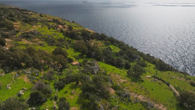 Cinematic drone flight over the rugged edge of Dingli Cliffs in Malta, showing contrast between green plateau and deep blue mediterranean sea
