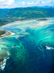 An underwater waterfall off the coast of Mauritius. Aerial view of Le Morne Mountain and a coral reef. A beautiful panoramic view of the tropical island. © Vera