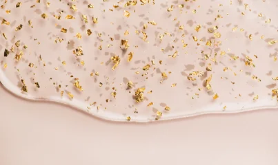Serum fluid 24k gold gel facial cream smear on beige pastel background. Beauty cosmetic product smudge, pure transparent lotion with gold particles, skin care jelly serum, top view Luxury moisturizer. © Subbotina Anna
