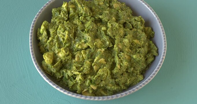 Chunky guacamole - famous Mexican avocado salsa in a blue bowl on a blue background. 