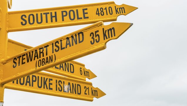 Yellow signs, signpost with different destinations, cities and distances, Bluff, South Island, New Zealand
