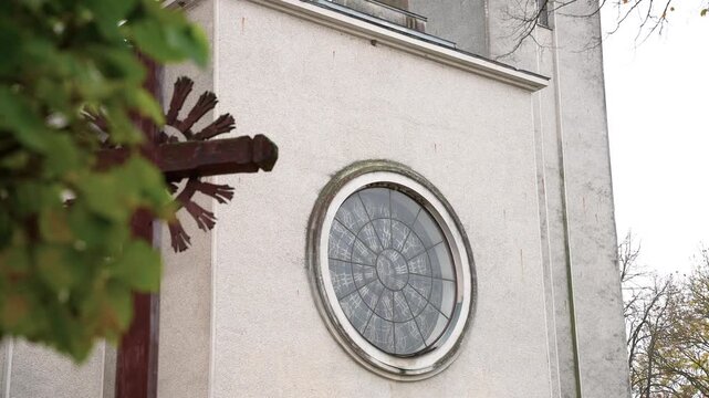 Detailed close-up of Pilvi&scaron;kiai Holy Trinity Church's round stained-glass window. Soft natural light enhances the intricate glass patterns and surrounding architecture.