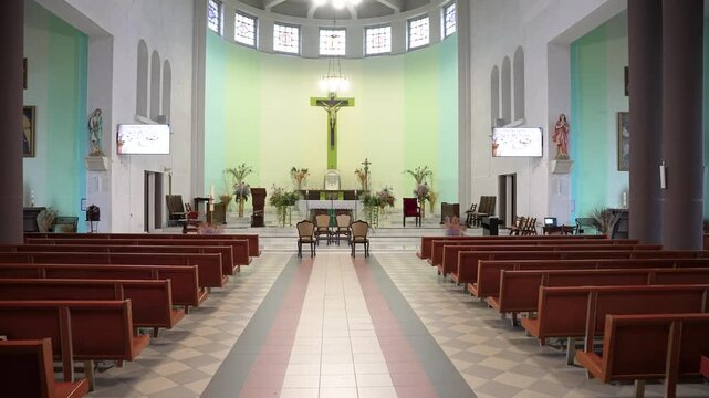Wide-angle view of the serene interior of Pilvi&scaron;kiai Holy Trinity Church, Lithuania. Natural light illuminates the altar and stained glass, creating a peaceful atmosphere. No people present.