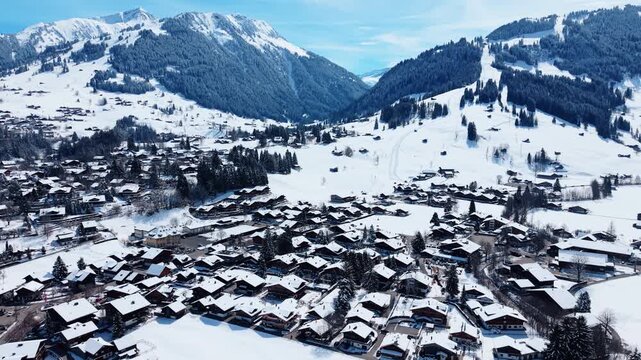 Aerial: Gstaad cityscape with snow in winter during the day in Canton of Bern, Switzerland, orbit drone shot