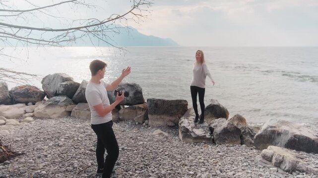Male photographer directing a female model with Lake Geneva behind during the day in Montreux, Switzerland, gimbal shot
