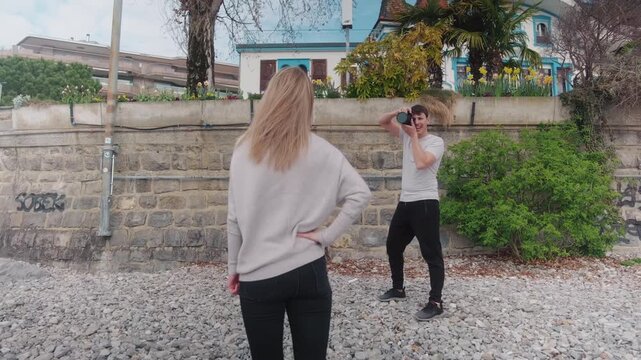 Male photographer directing a female model at a beach during the day, gimbal shot