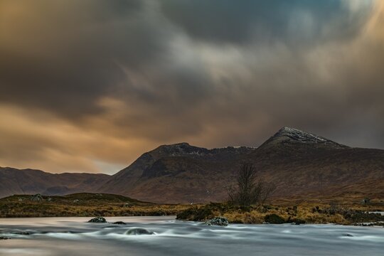 River Ba with mountain peaks of Meall a&acute;Bh&uuml;iridh and Clach Leathad in the background and dramatic clouds, Glen Coe, Rannoch Moor, west Highlands, Scotland, United Kingdom