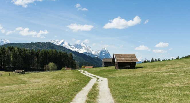 Hay stall in meadow on dirt road with snow-capped Karwendel Mountains, Werdenfelser Land, Upper Bavaria, Bavaria, Germany