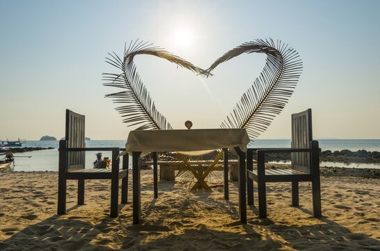 Laid table with a heart of palm fronds, sunset, Koh Samui, Gulf of Thailand, Thailand