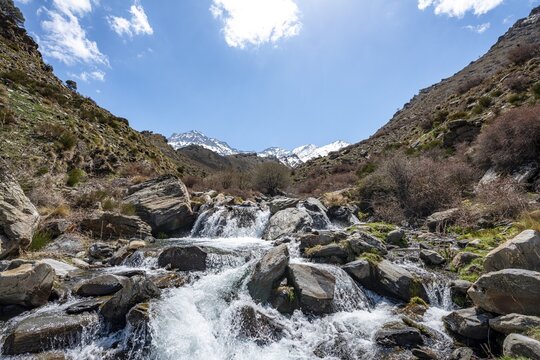 Mountain stream Rio Valdeinfierno, hiking trail near Junta de los Rios, behind Sierra Nevada with summits Mulhac&eacute;n and La Alcazaba, snow-covered mountains near Granada, Andalusia, Spain