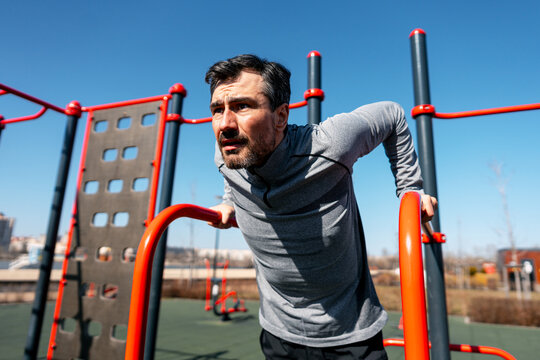 Man doing dips on parallel bars at outdoor gym