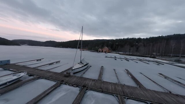Sailboat moored at icy pier in Telemark Norway winter evening