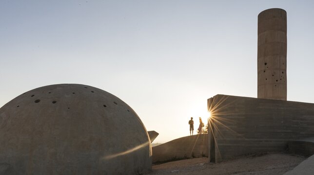 Two people standing at the concrete monument, Monument of the Negev Brigade, Sun in the evening, Be'er Sheva, Israel
