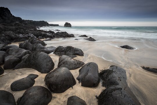 Skar&eth;sv&iacute;k Beach, sandy beach with large round black volcanic rocks, waves at the sea, bad weather, bulb exposure, West Iceland, Iceland