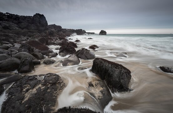 Skar&eth;sv&iacute;k Beach, sandy beach with large round black volcanic rocks, waves at the sea, bad weather, bulb exposure, West Iceland, Iceland