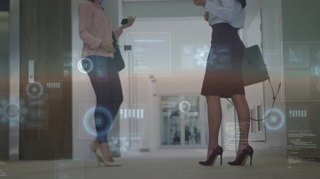 Business colleagues walking hallway, approaching colleague sharing phones under HUD, tapping heels