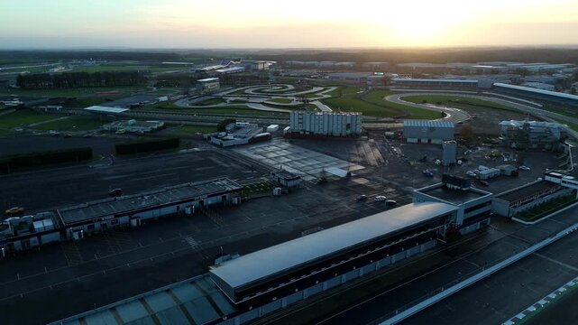 High angle aerial of the Silverstone high-speed Formula One circuit and surrounding infrastructure in the United Kingdom during a winter sunset.