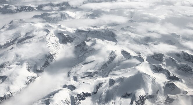 View from the plane to snow-covered mountainous landscape, bird's eye view, Greenland